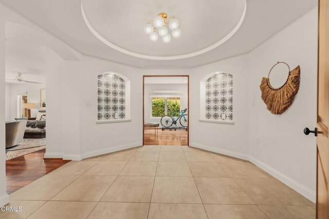 foyer with tile patterned floors, baseboards, and a raised ceiling