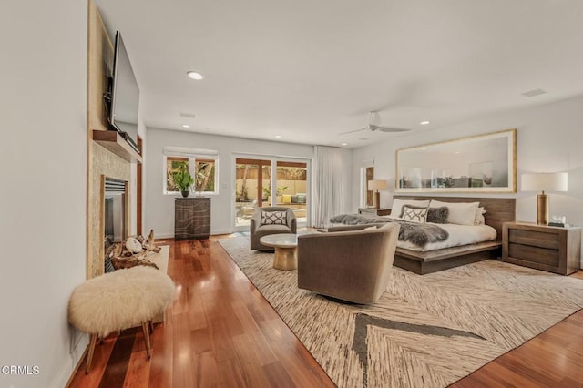 bedroom with recessed lighting, baseboards, wood finished floors, and a fireplace