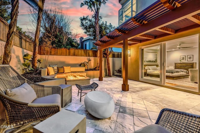 patio terrace at dusk with an outdoor living space with a fire pit, fence, and a pergola