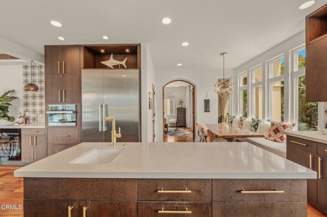 kitchen with open shelves, a sink, light countertops, stainless steel appliances, and modern cabinets