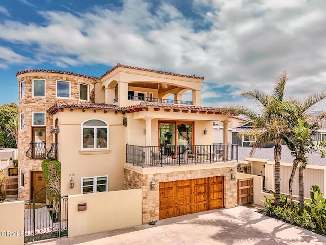 mediterranean / spanish house with stone siding, stucco siding, and a balcony