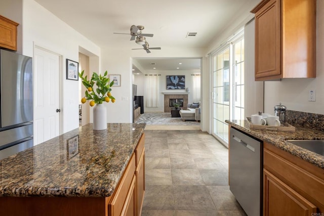 1185 Parkview Dr, Oceanside, CA 92057 - kitchen with brown cabinets, stainless steel appliances, ceiling fan, and a tiled fireplace