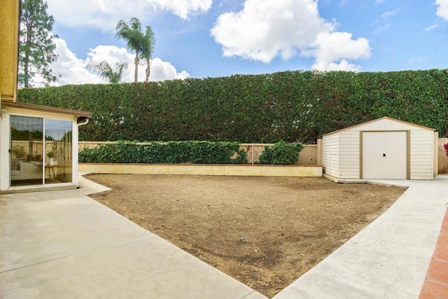 view of yard with a patio, a fenced backyard, a shed, and an outbuilding