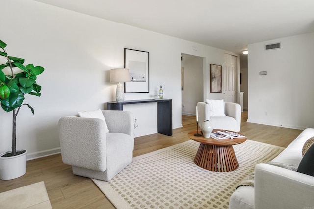 living area with light wood-style floors, baseboards, and visible vents