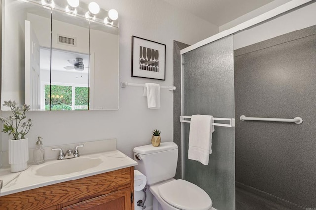bathroom with vanity, visible vents, toilet, and a shower stall