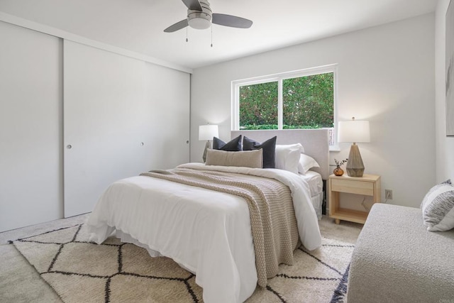 bedroom with a ceiling fan, light carpet, and a closet