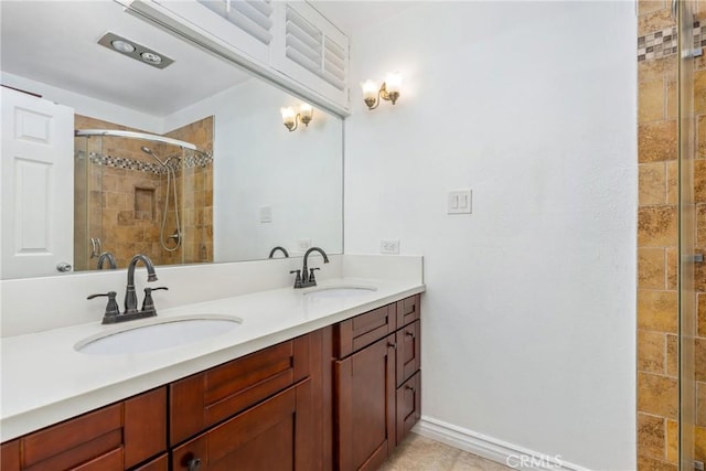 full bath with double vanity, baseboards, a shower stall, and a sink