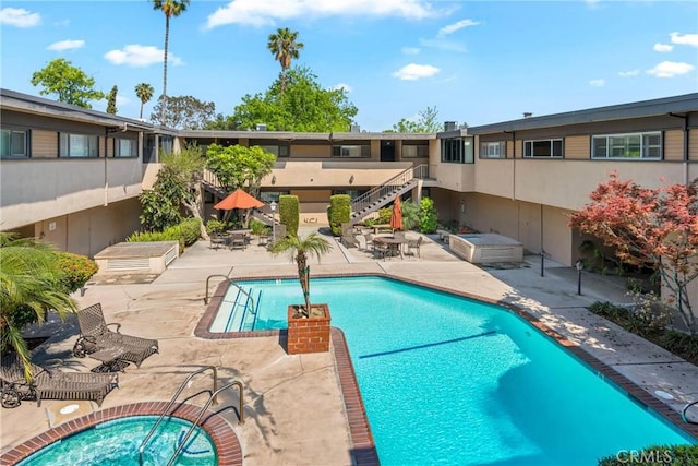 pool featuring a patio, a hot tub, and stairway