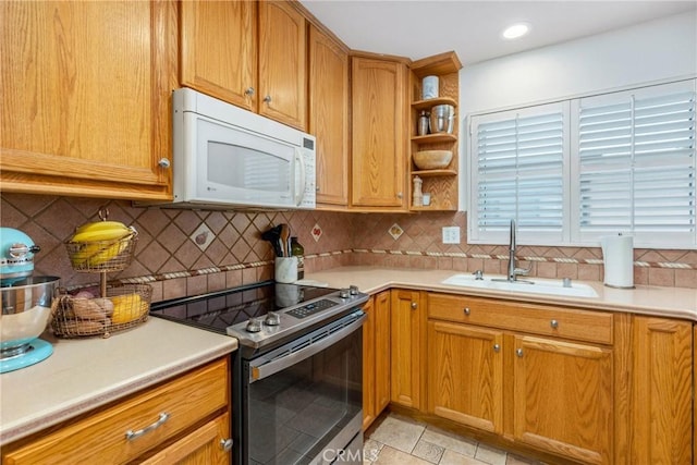 kitchen featuring a sink, stainless steel electric range, white microwave, and light countertops
