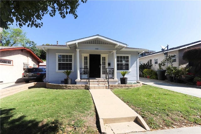 bungalow-style home featuring covered porch and a front yard