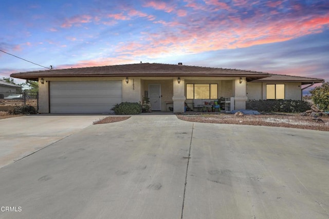 single story home featuring a garage, stucco siding, and concrete driveway