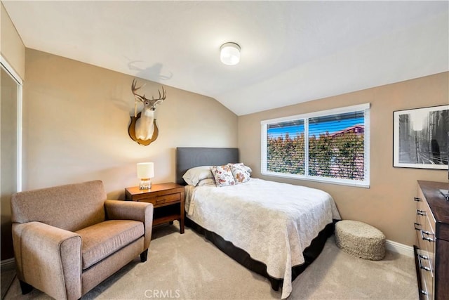 bedroom with baseboards, light carpet, and lofted ceiling
