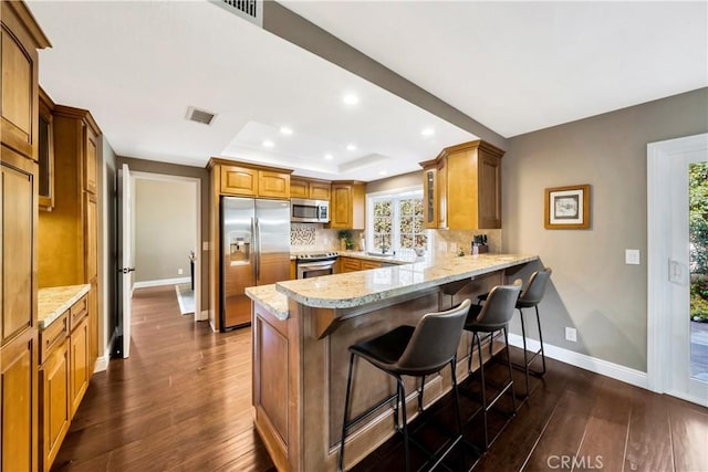 kitchen with dark wood-style flooring, visible vents, appliances with stainless steel finishes, baseboards, and a peninsula