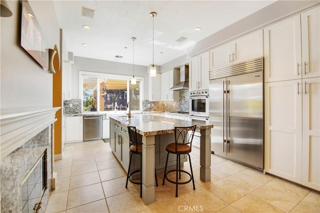 3988 Keri Way, Fallbrook, CA 92028 - kitchen with appliances with stainless steel finishes, wall chimney exhaust hood, backsplash, white cabinetry, and a kitchen bar