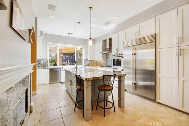 3988 Keri Way, Fallbrook, CA 92028 - kitchen featuring stainless steel appliances, wall chimney exhaust hood, tasteful backsplash, white cabinets, and a breakfast bar
