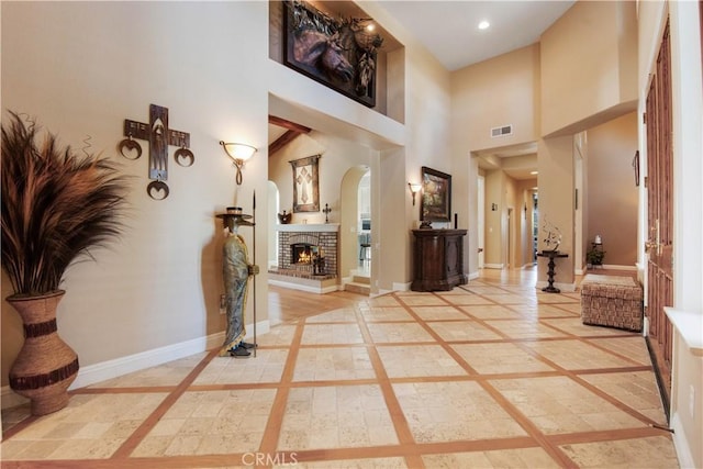 3988 Keri Way, Fallbrook, CA 92028 - entrance foyer featuring inlaid floor details, arched walkways, baseboards, a towering ceiling, and a brick fireplace