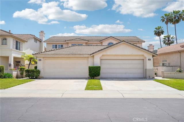 mediterranean / spanish house with an attached garage, stucco siding, a tile roof, and concrete driveway