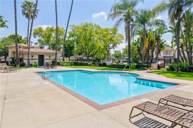 community pool with a patio area and fence