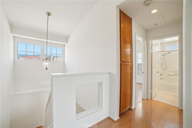 hall with an inviting chandelier, attic access, recessed lighting, light wood-style flooring, and an upstairs landing