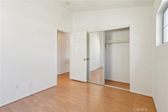 unfurnished bedroom with baseboards, wood finished floors, and a closet