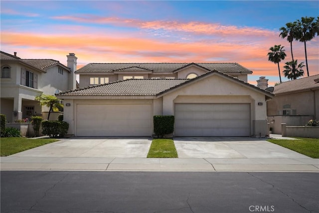 view of front of home featuring a garage, stucco siding, a tiled roof, and concrete driveway