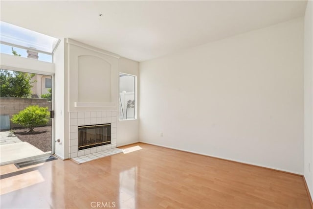 unfurnished living room featuring light wood-style floors, baseboards, and a tile fireplace