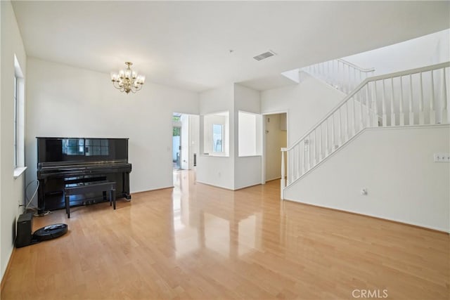 living room with stairway, visible vents, wood finished floors, and a chandelier