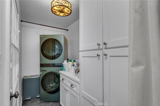 washroom featuring cabinet space and stacked washer / dryer