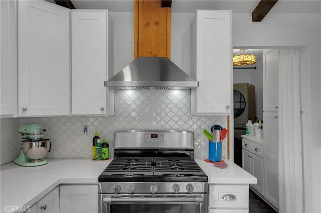 kitchen with wall chimney range hood, stainless steel range with gas stovetop, and white cabinets