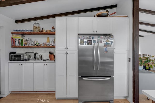 kitchen with tasteful backsplash, open shelves, light wood-type flooring, white cabinets, and stainless steel fridge