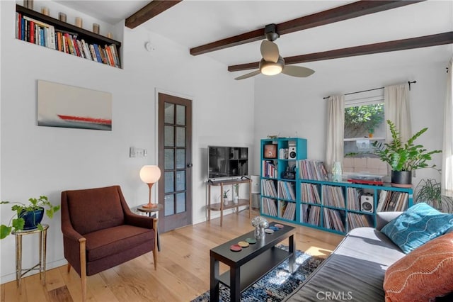 living area with ceiling fan, beam ceiling, and wood finished floors