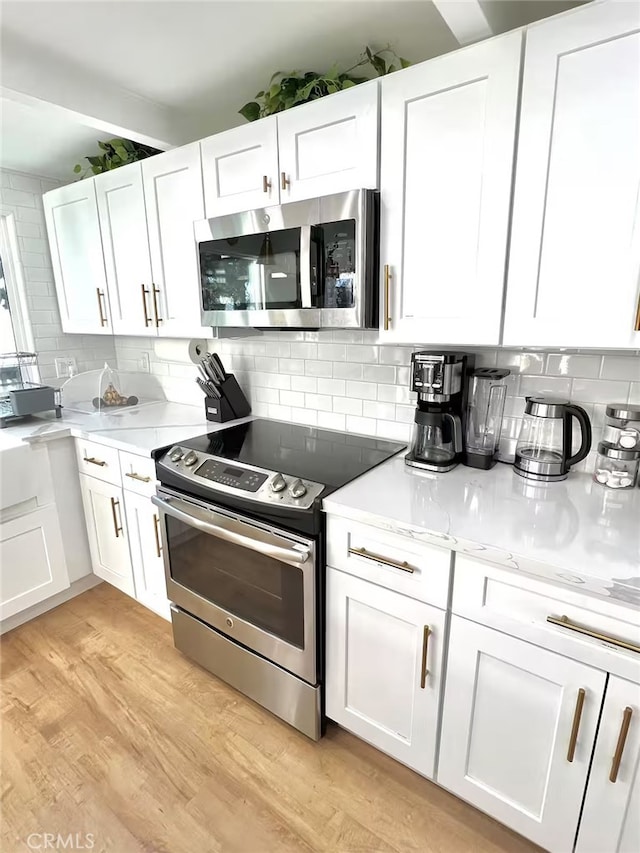 2012 Poplar Dr, Running Springs, CA 92382 - kitchen featuring appliances with stainless steel finishes, white cabinets, backsplash, and light wood-style flooring