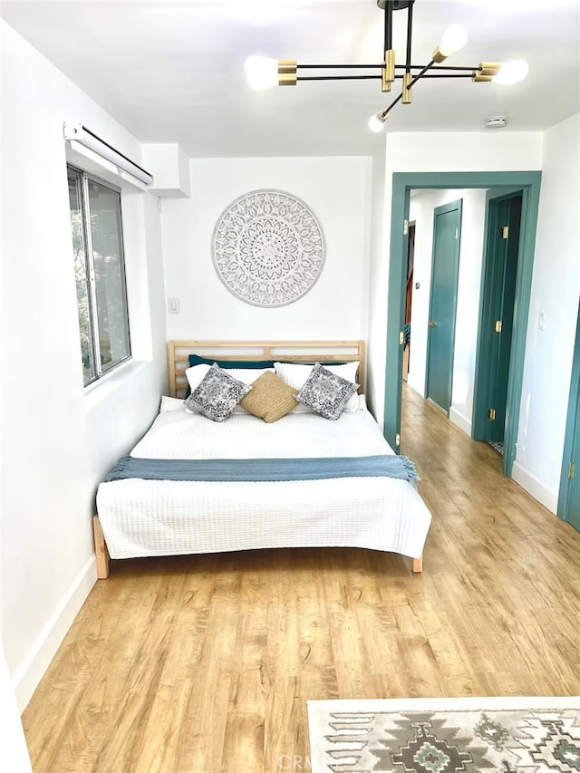 bedroom with baseboards, wood finished floors, and a notable chandelier