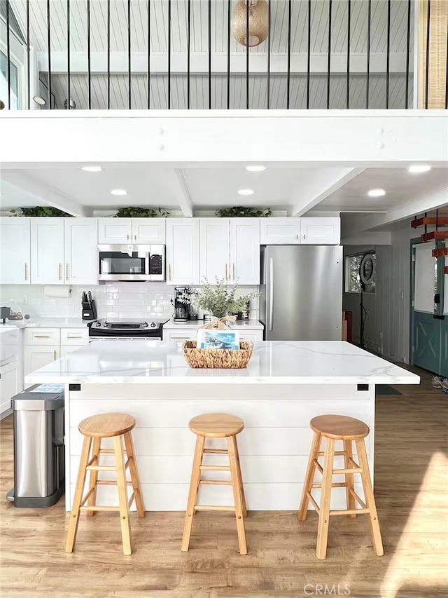 2012 Poplar Dr, Running Springs, CA 92382 - kitchen with appliances with stainless steel finishes, light wood-style floors, white cabinetry, decorative backsplash, and beamed ceiling