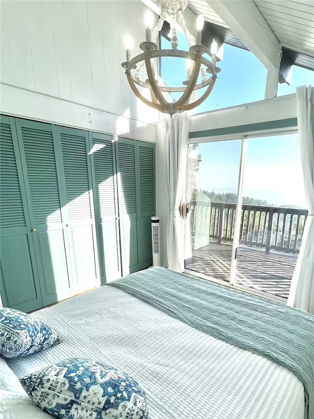 bedroom with access to outside, vaulted ceiling, and a chandelier