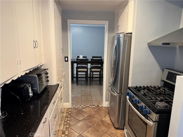 812 N Dickel St, Anaheim, CA 92805 - kitchen with stainless steel appliances, tile patterned floors, white cabinets, wall chimney range hood, and baseboards