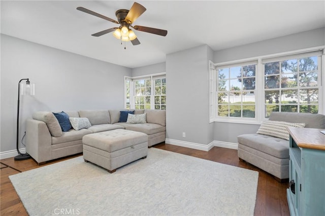 living room with a ceiling fan, baseboards, and dark wood-style floors