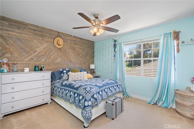 bedroom with light colored carpet, ceiling fan, and wooden walls