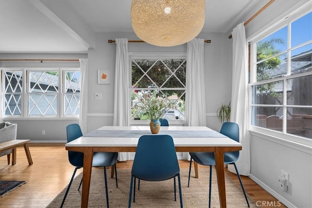 dining space with baseboards and light wood-style flooring