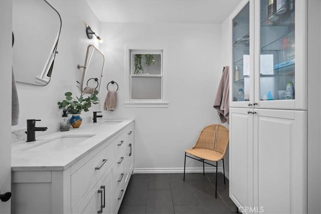 full bathroom featuring a sink, tile patterned floors, baseboards, and double vanity