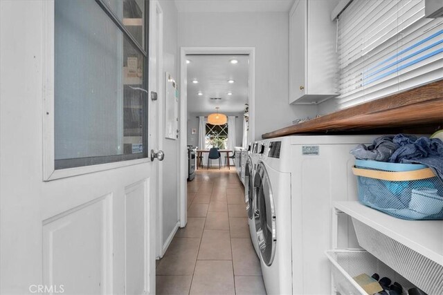 laundry area featuring tile patterned floors, separate washer and dryer, and cabinet space