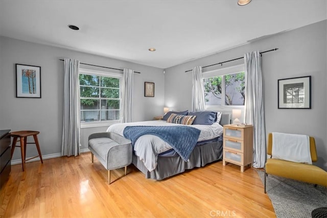 bedroom with baseboards, multiple windows, and light wood-style flooring
