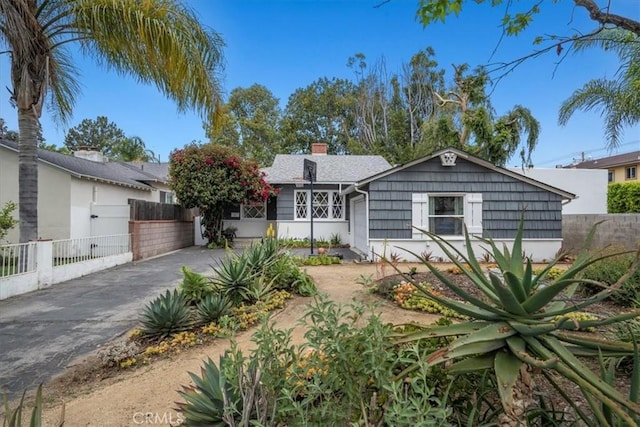 view of front of home with fence, driveway, and a chimney