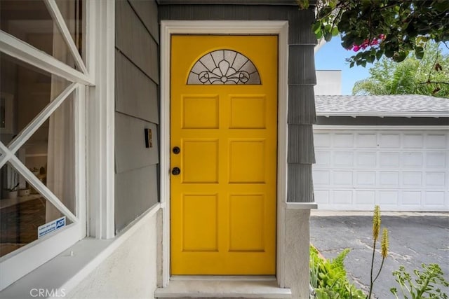 doorway to property featuring roof with shingles