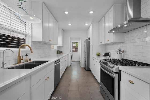 kitchen with a sink, appliances with stainless steel finishes, tasteful backsplash, and wall chimney exhaust hood