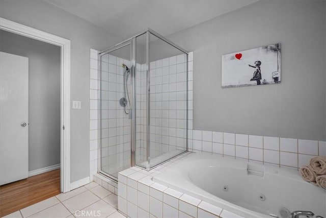 bathroom with a jetted tub, baseboards, tile patterned floors, and a shower stall