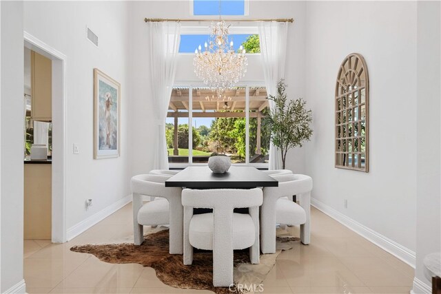 dining space featuring a healthy amount of sunlight, a towering ceiling, tile patterned flooring, and a chandelier