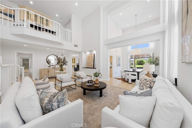 living room featuring recessed lighting, a notable chandelier, and a towering ceiling