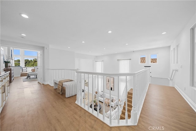 hallway with recessed lighting, light wood-style flooring, baseboards, and an upstairs landing