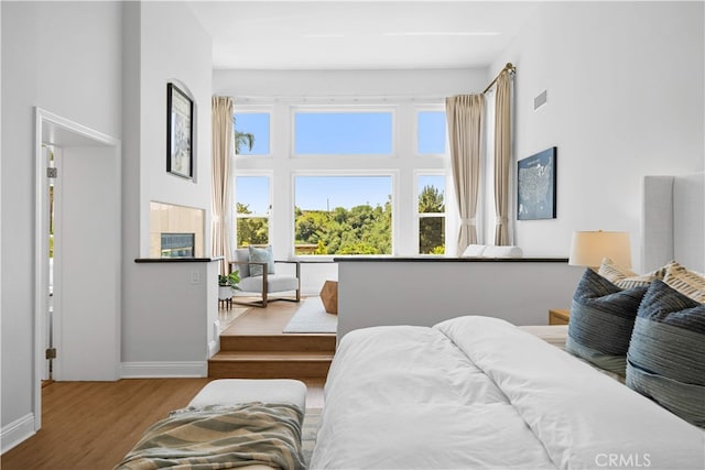bedroom with baseboards, a towering ceiling, and wood finished floors